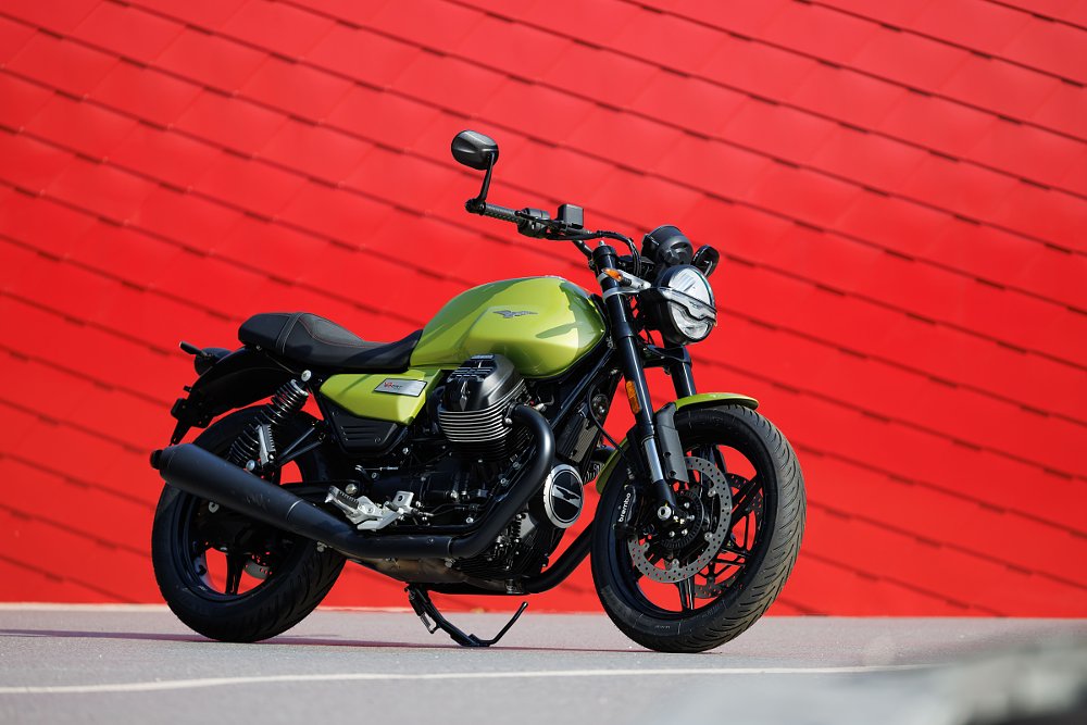 green V7 Sport parked in front of a red wall
