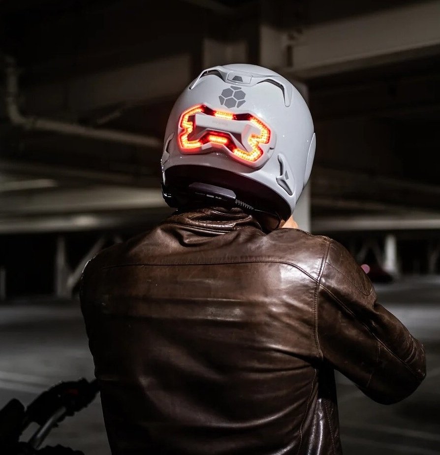 photo of a rider from behind in a dark parking garage with the red light lit up on the back of the helmet