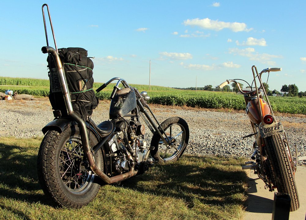 Two custom motorcycles with sissy bars.