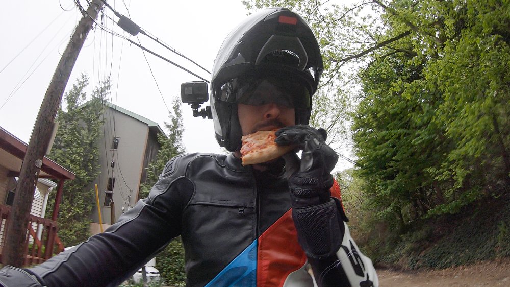 eating some pizza while riding a motorcycle utilizing the AGV Sportmodular Helmet