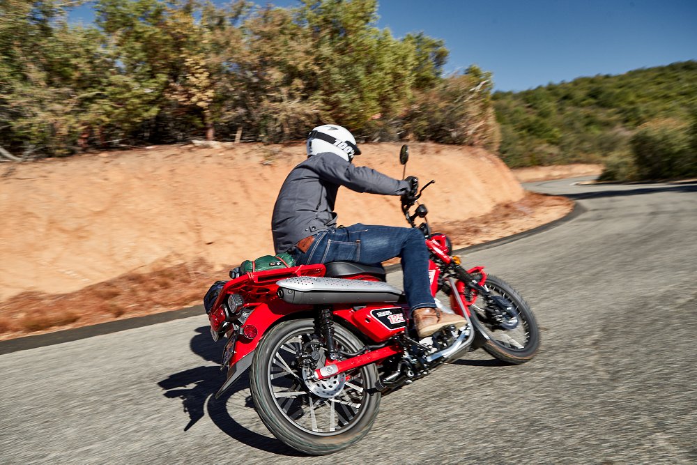 Honda Trail 125 turning left through a sharp curve on a back road
