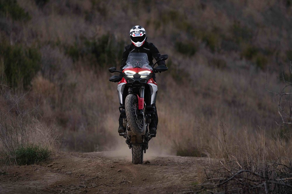 Ducati Multistrada V4 doing a wheelie on a dirt trail