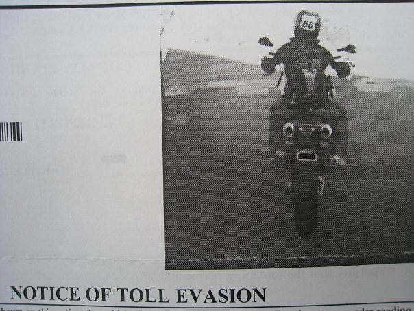 Grainy black-and-white photo showing a notice of toll evasion on a motorcycle