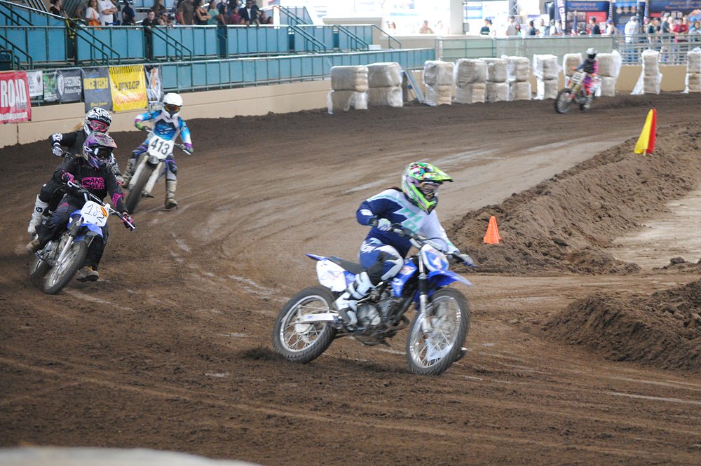 Jen racing a TT-R 125 in an indoor arena during a flat track race