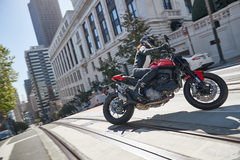 A female rider pilots the Ducati Monster through a busy city street corner