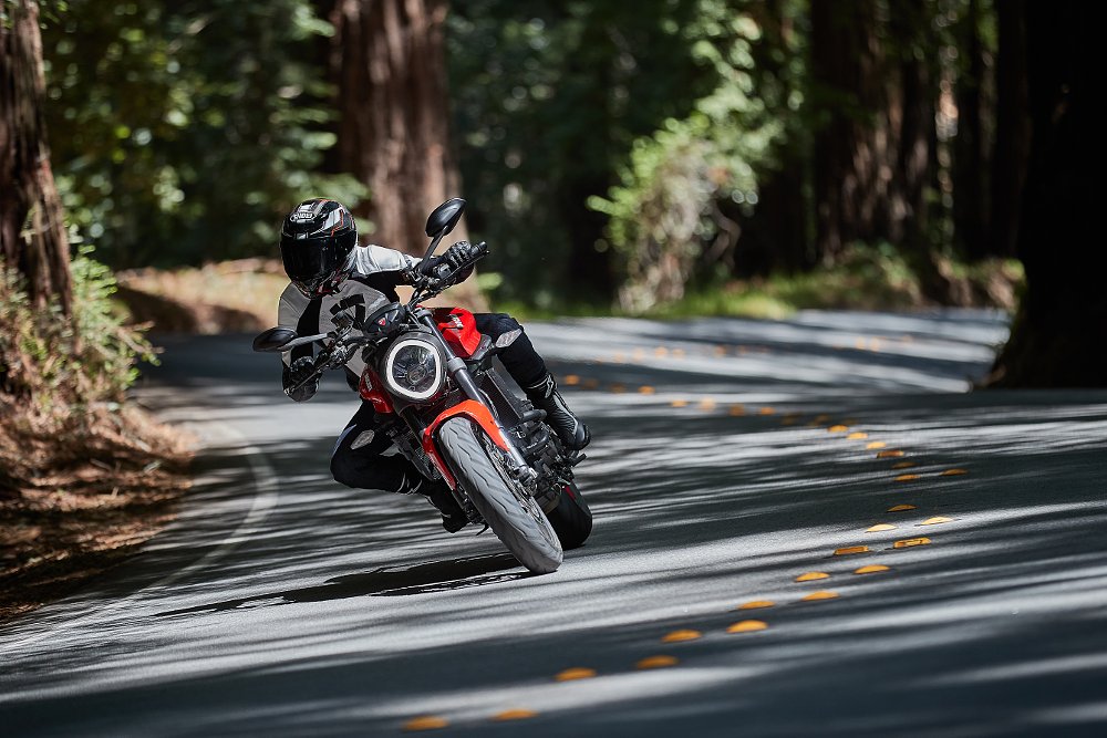 A female rider on the Ducati Monster on a forested road