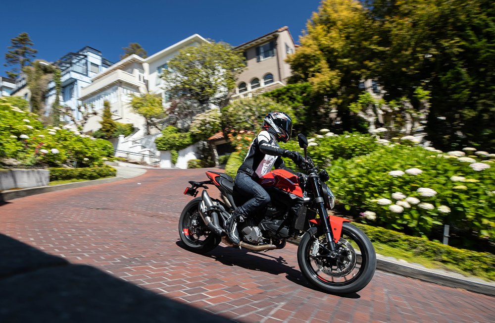 A female rider pilots the Ducati Monster up a brick street hill