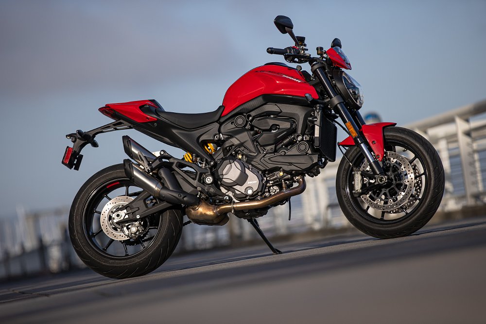 A bright red Ducati Monster posed on a sidewalk