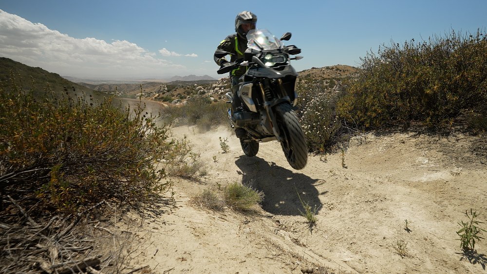 BMW R 1250 GS jumping along a dirt trail