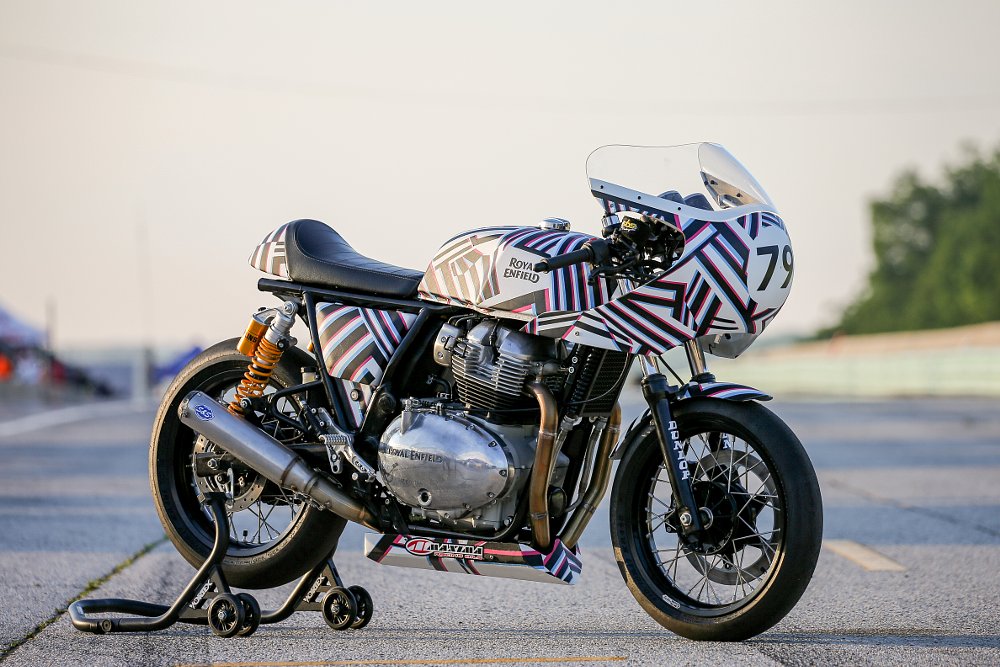 Scarlett's completed Royal Enfield racebike sits on display on the race track, it has vibrant colors and graphics