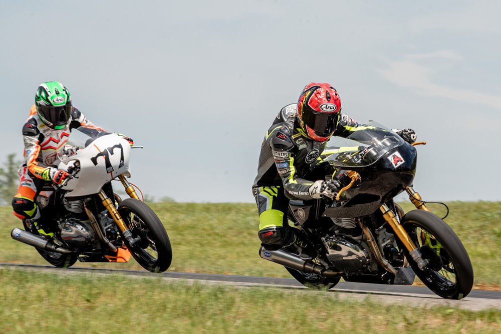 Melissa and CJ on board their own race motorcycles go around a corner together.