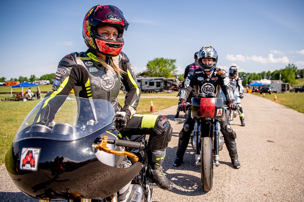 Melissa Paris in full leathers on her race motorcycle waits to take off on the track with the group behind her.
