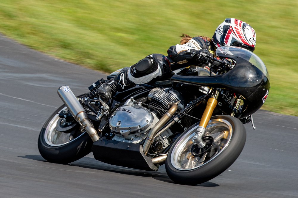 A BTR racer is leaned over in the corner going fast on her race motorcycle.