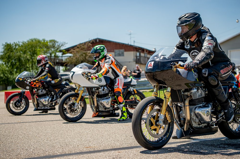 Three racers on board their race motorcycles line up in a row for practice.