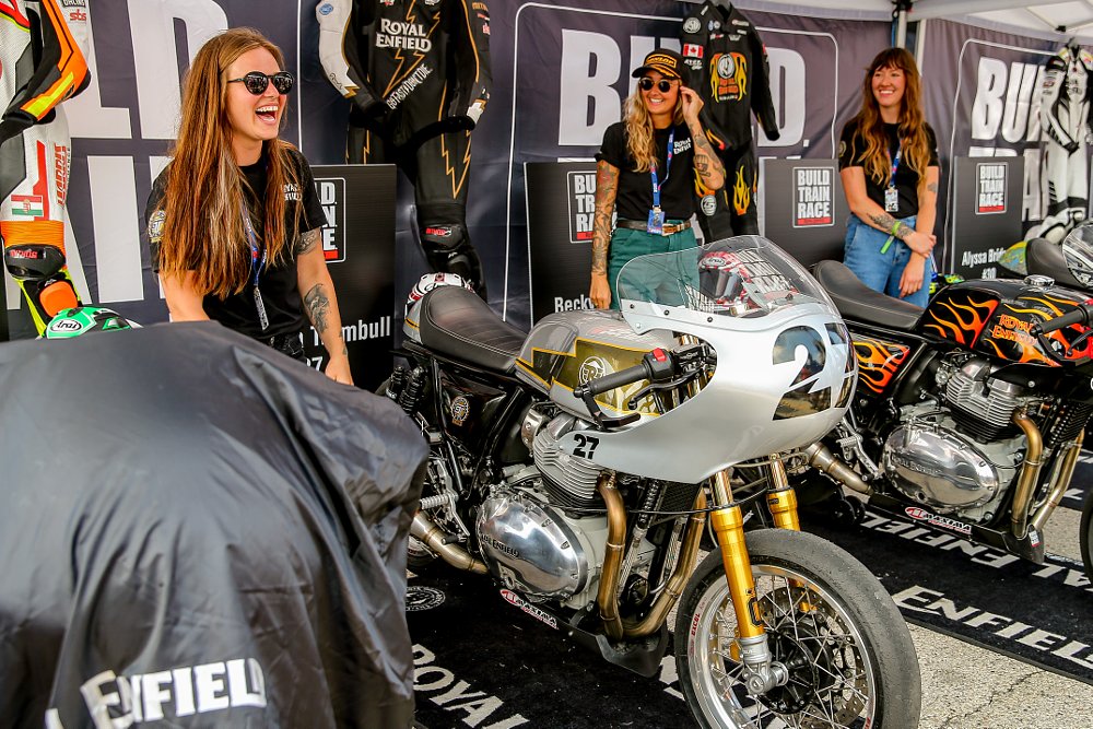 Three women racers unveil their Royal Enfield race bikes in the professional road racing paddock.