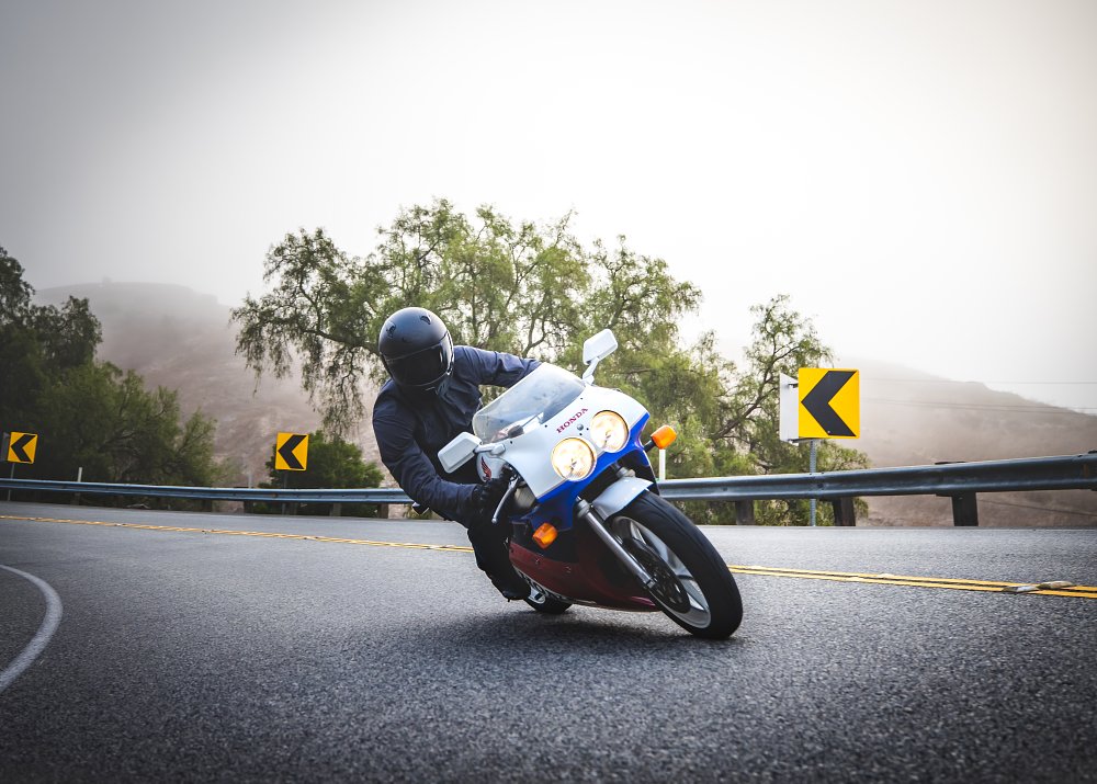 A Honda RC30 rides at camera through a right-hand curve.