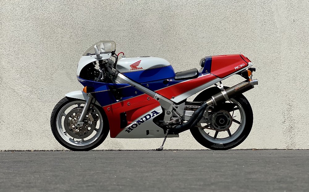 Left profile of a Honda RC30 in front of a gray wall.
