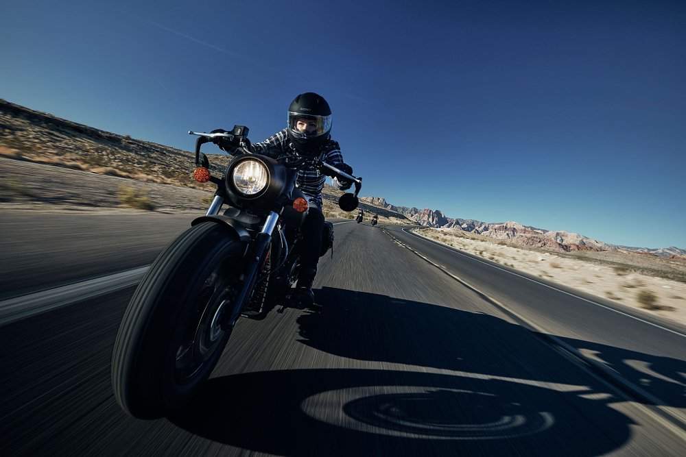 A close up front shot of the Indian Scout Bobber motorcycle in motion on a big empty desert road