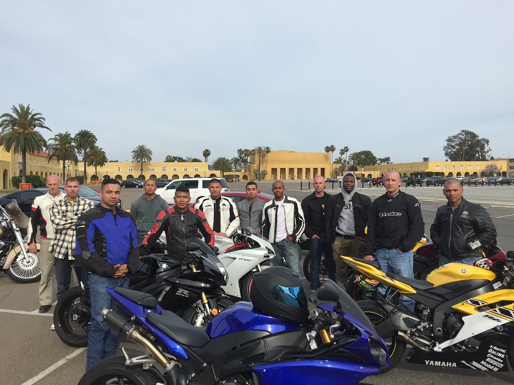 A group of street bike riders and their motorcycles gather for a group photo