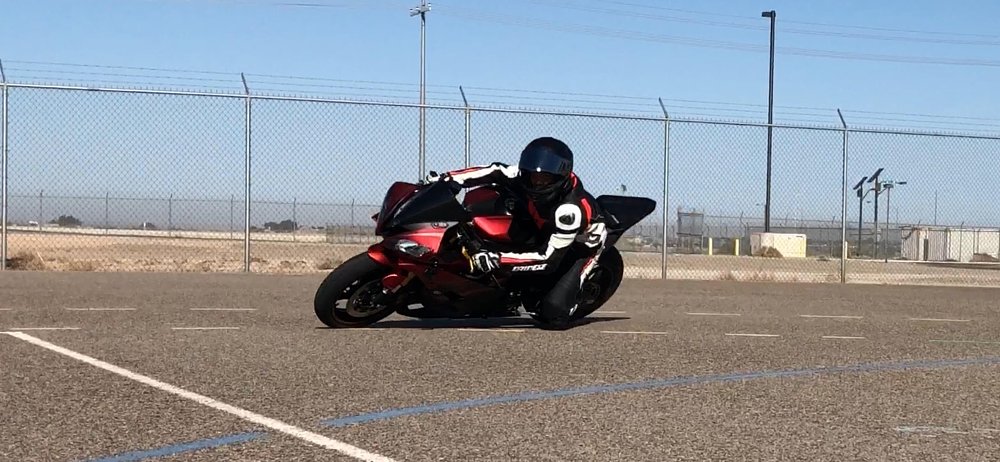 A rider practices cornering drills in a parking lot on a sportbike