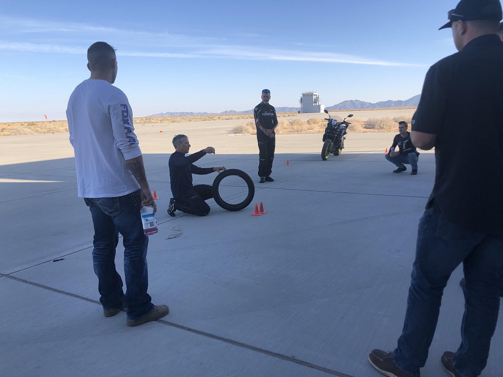 A YCRS instructor poses with a motorcycle tire and is pointing out important lessons to students watching