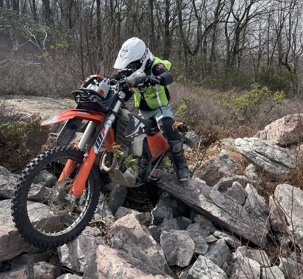 Morgan on his dirt bike with chainsaw traversing rocks