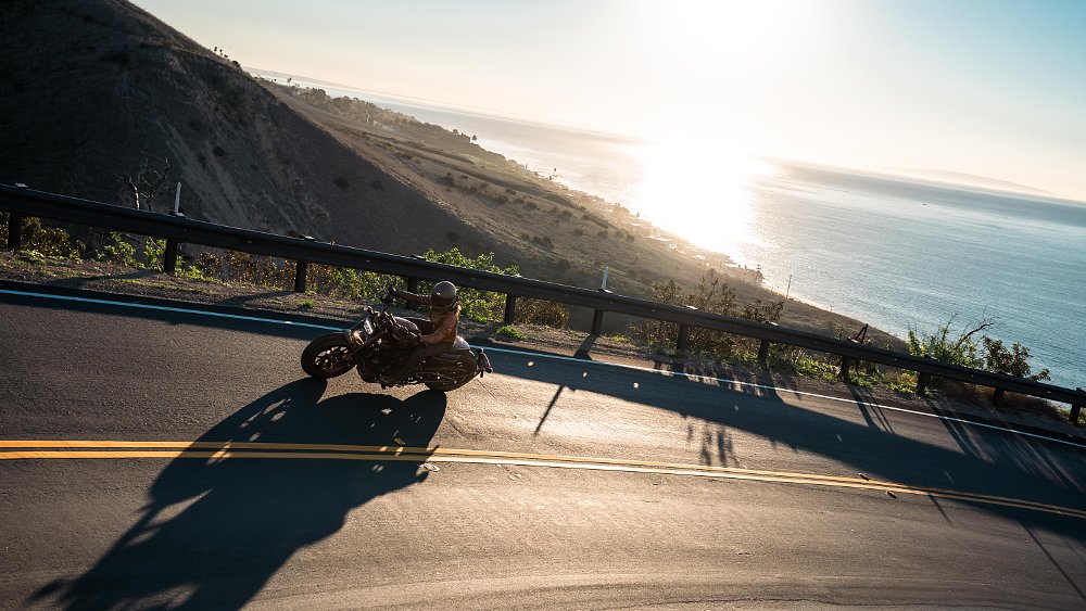A female rider pilots the Sportster S motorcycle in a dramatically backlight canyon road