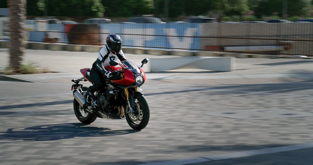 A female rider is riding down a busy city street on the Speed Triple 1200 RR