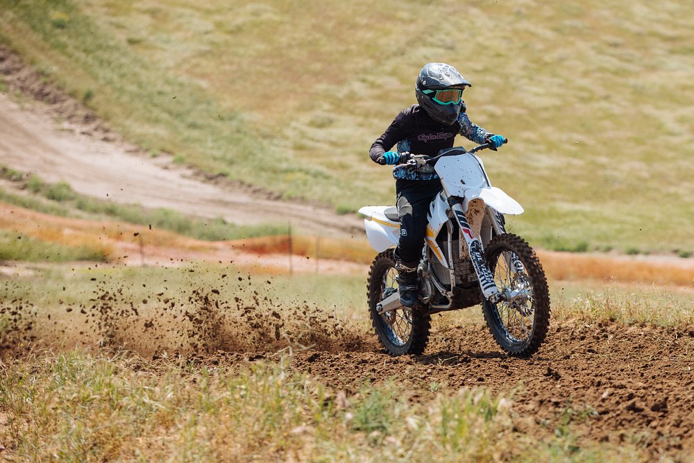 A female student exits the corner with dirt roost flying off the rear tire