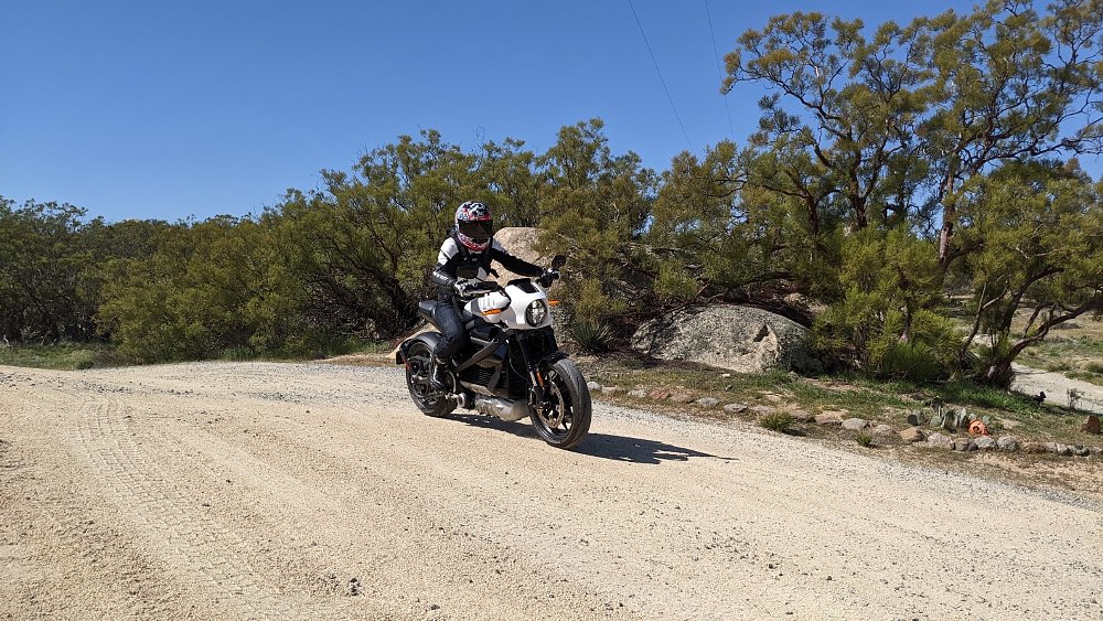 A female rider pilots the LiveWire ONE motorcycle along a dirt road
