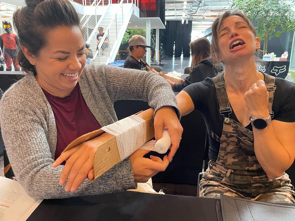 Two students practice applying bandages and splint in a mock scenario of an injury