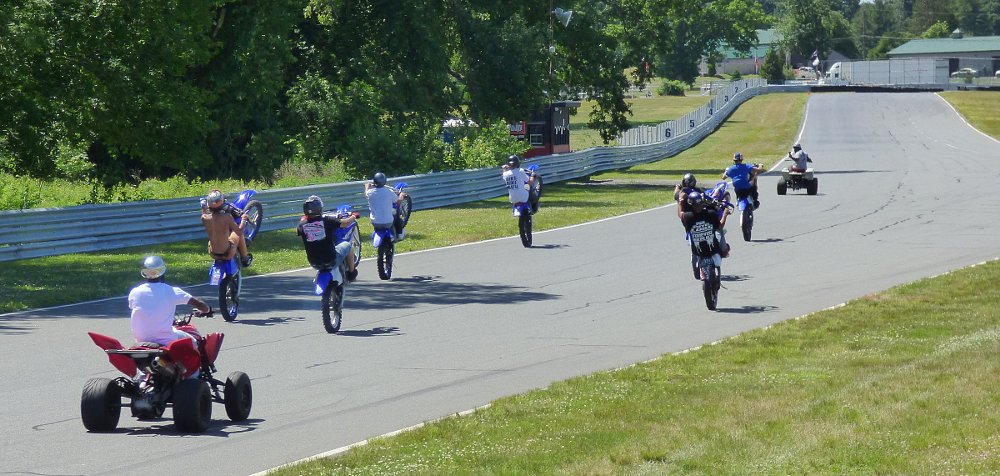 wheelie racers start off around the track with observers on ATVs