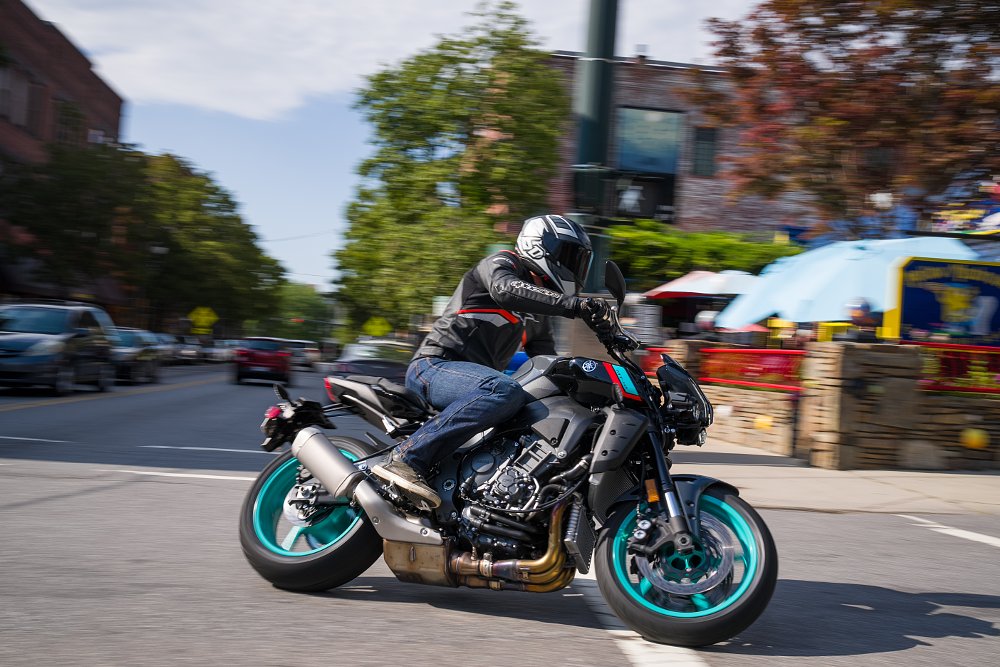 2022 Yamaha MT-10 leaning through a left turn in front of an outdoor restaurant in a city