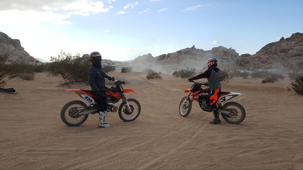 Two dirt bike riders wait in the campsite before heading out on a ride