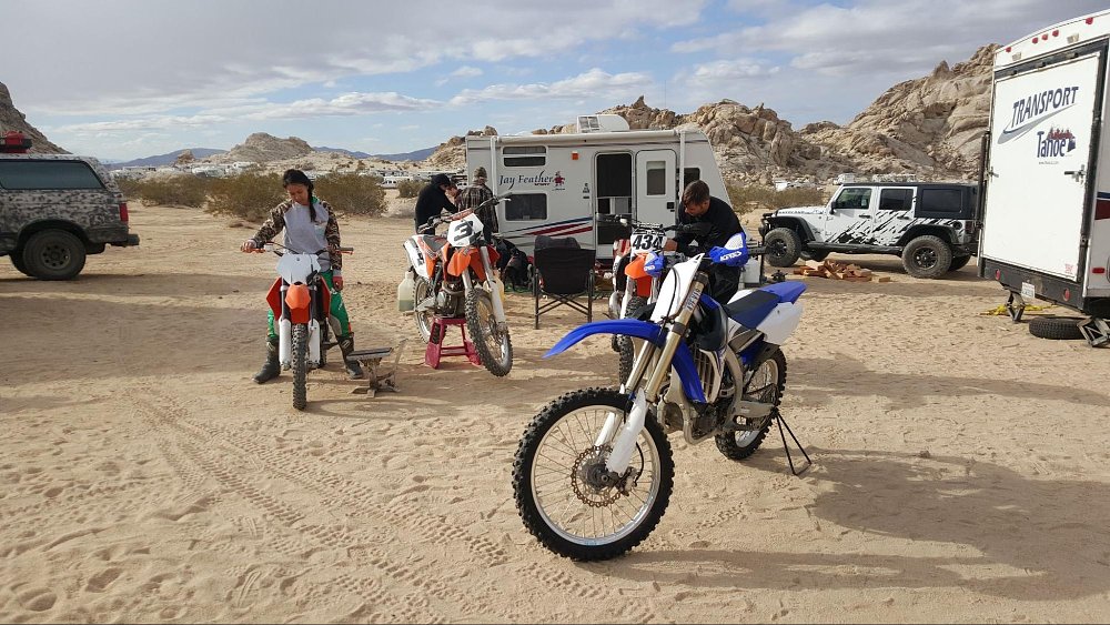 A group of dirt bike riders gather in their campsite and prep their motorcycles