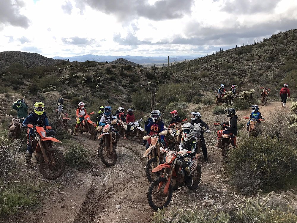 A large group of off road riders gather at a trailhead in arizona