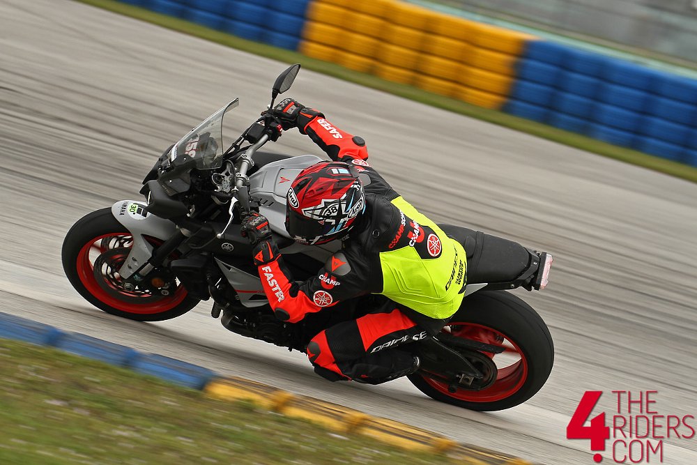 A rider coach in bright colored leather suit races on a pavement racetrack