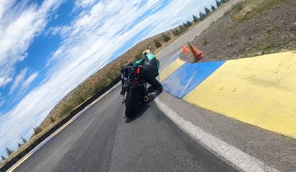 Jen Dunstan is knee down over the curbing at the apex of the corner from a rear view angle