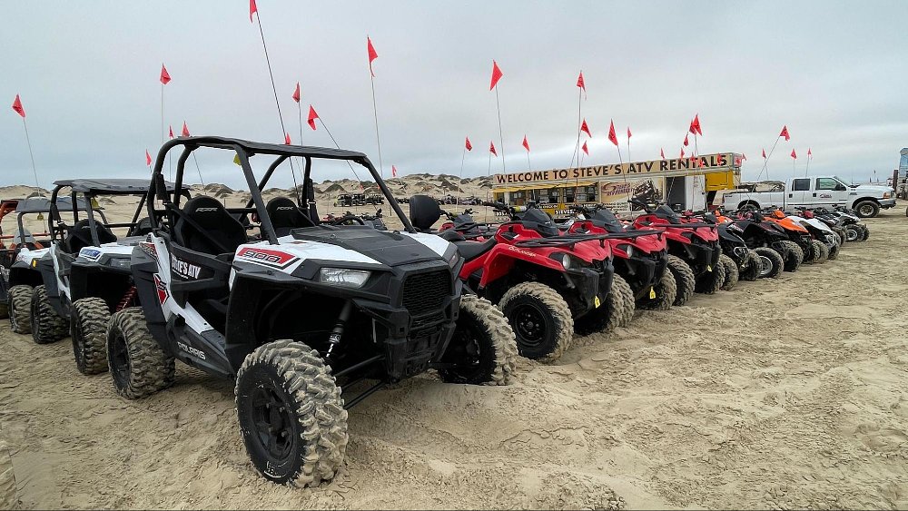 A photo of a fleet of ATV rentals sitting on the oceano dunes beach