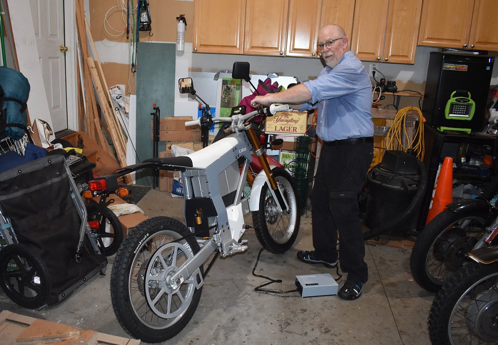 CAKE Kalk& charging in the garage with author standing beside it
