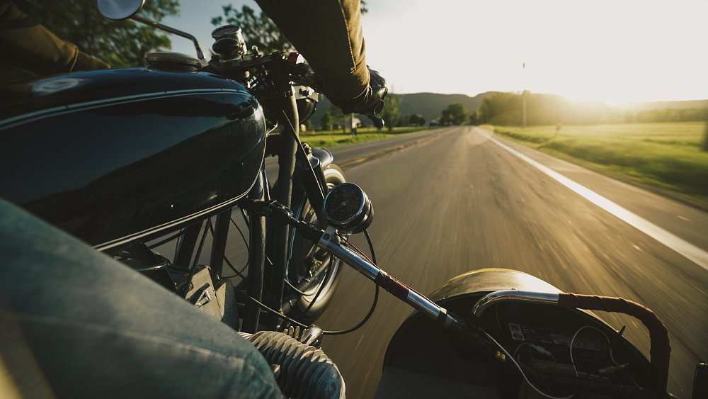 Point-of-view of being on board a vintage sidecar, riding into a sunset.