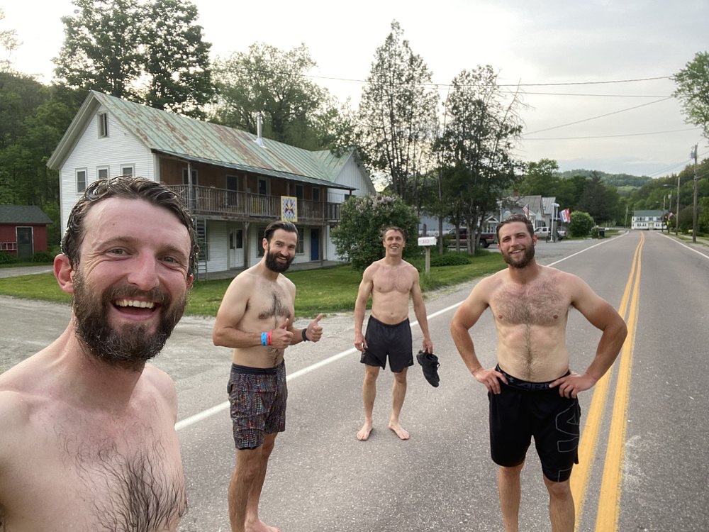 Four men standing in a rural town after swimming.
