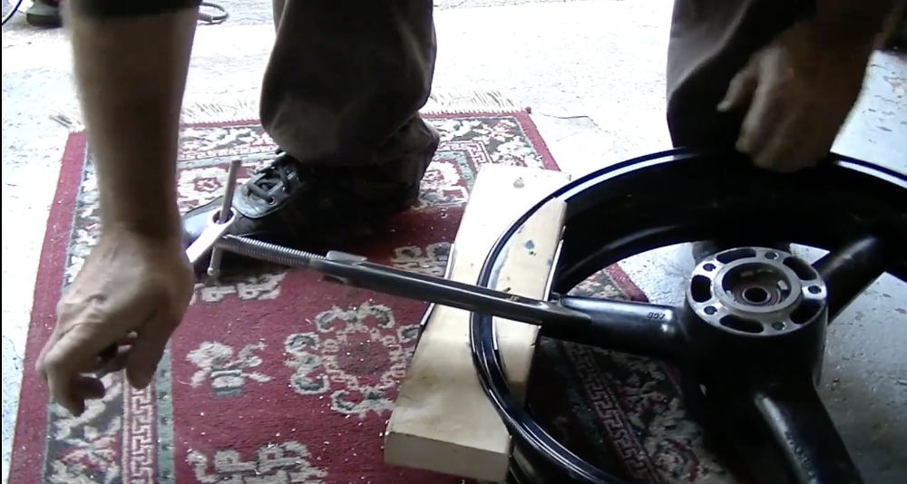 YouTube screen grab of someone trying to fix a dented motorcycle rim. 