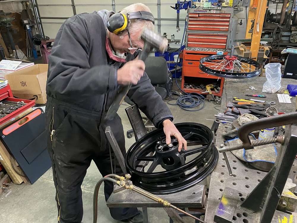 Hammering on the dented Versys 650 motorcycle rim. 
