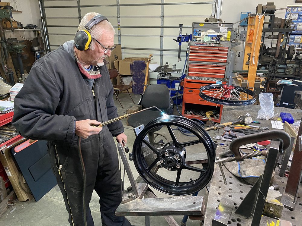 Heating a motorcycle rim with a torch prior to hammering on it. 