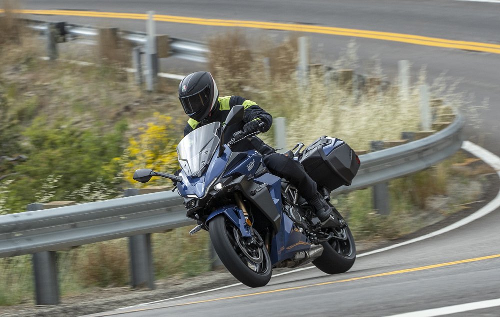 Suzuki's GSX-S1000GT+ going through a turn on a mountain road.