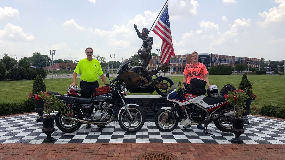 the writer with his father and their motorcycles in front of the Nicky Hayden statue
