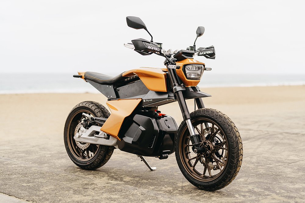 A front three quarter view of the Ryvid Anthem mini electric motorcycle on the beach