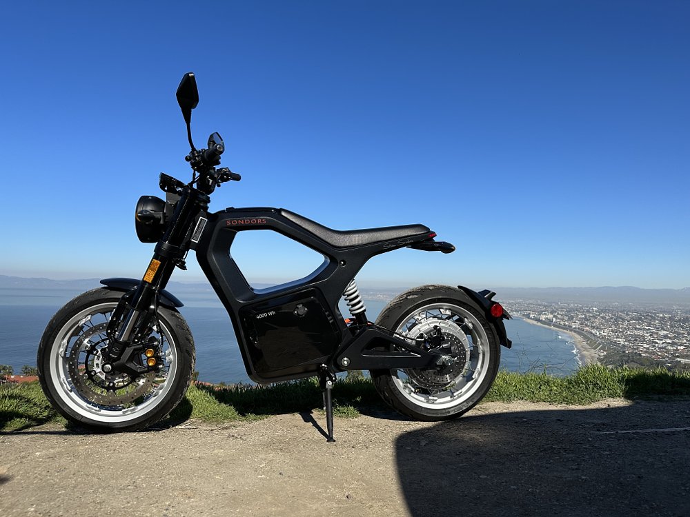 A side view of the Sondors Metacycle in all black parked in a grass park