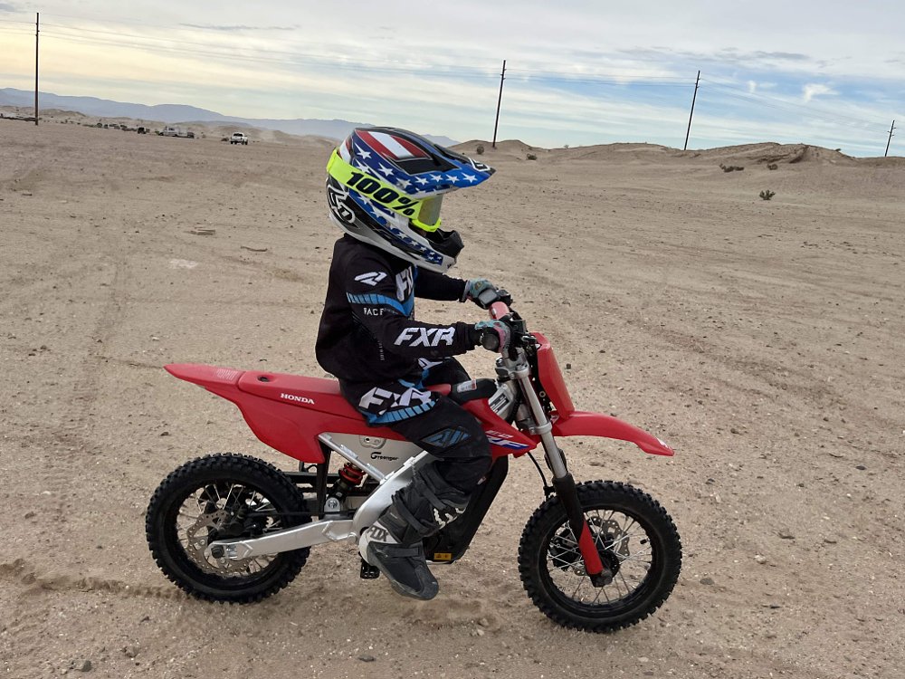 Child rider testing a Honda CRF-E2 mini dirt bike in the desert.